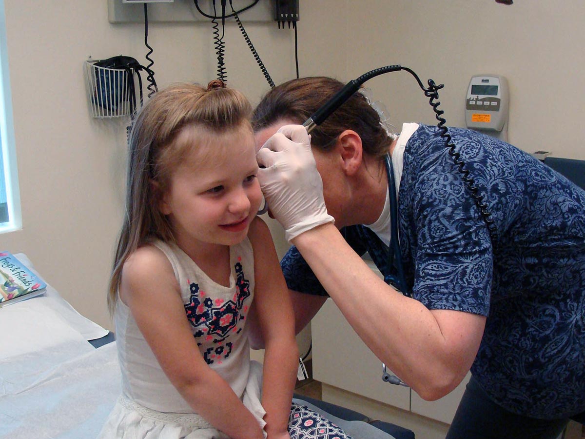 Young girl getting her ears examined by a provider