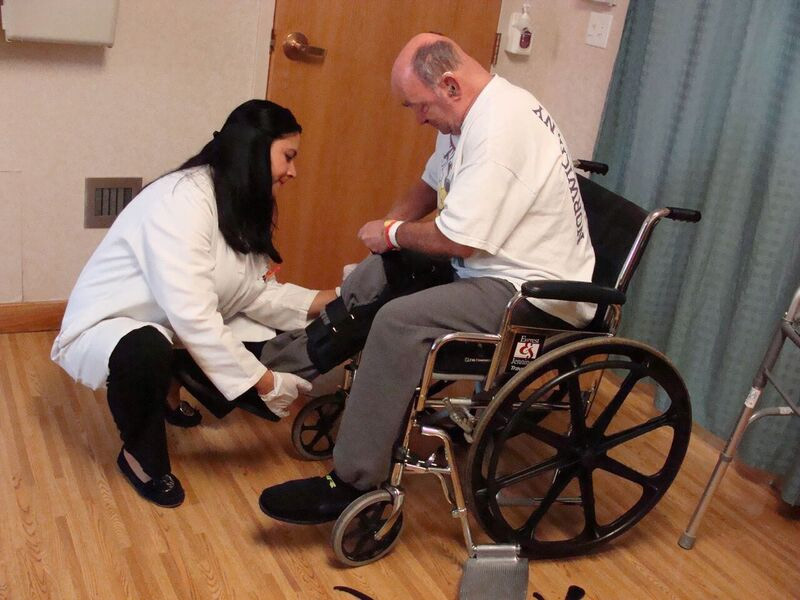 Man in wheelchair getting his leg examined by a provider