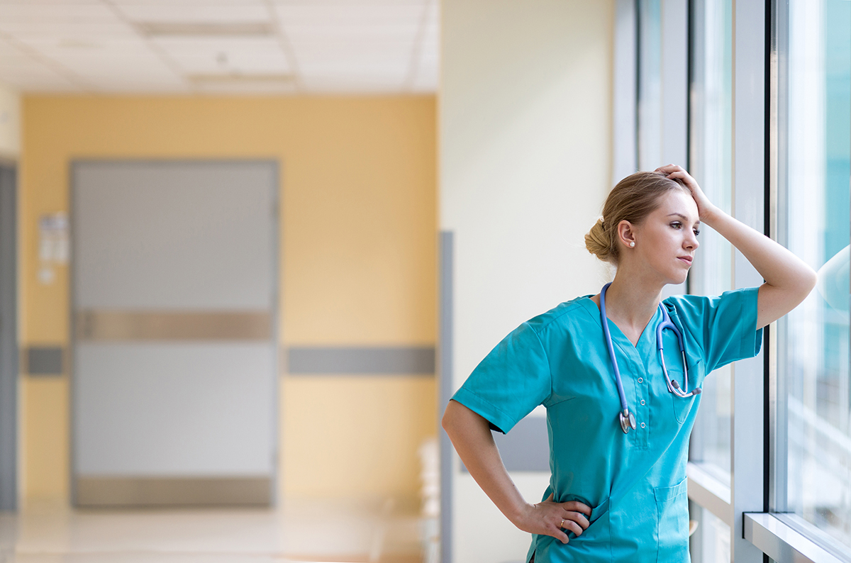 Tired female nurse in hospital corridor