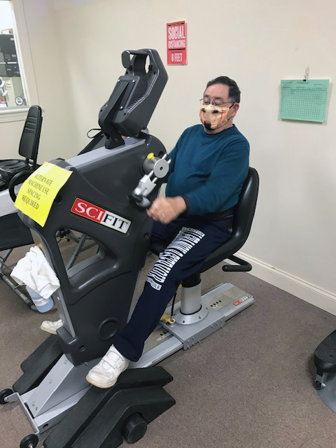 Man in mask on exercise machine at wellness center, Community Memorial Hospital