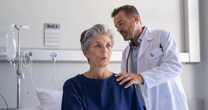 Doctor using stethoscope to check womans breathing