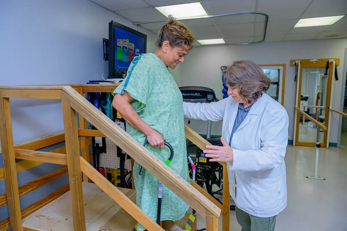 nurse helping patient walk down stairs