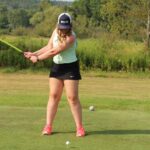 woman driving a golf ball down a fairway